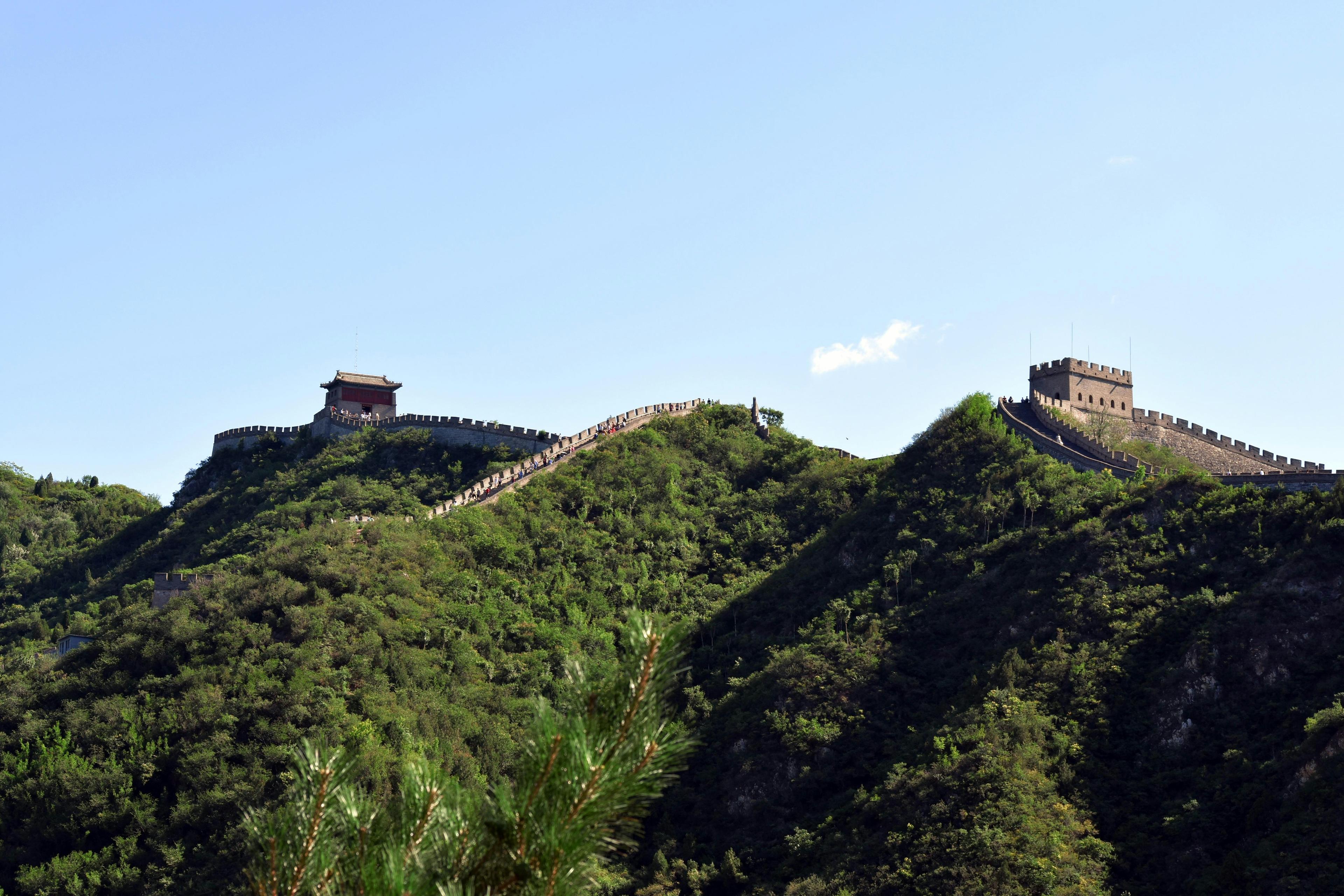 Great Wall of China winding through green mountains under clear blue sky