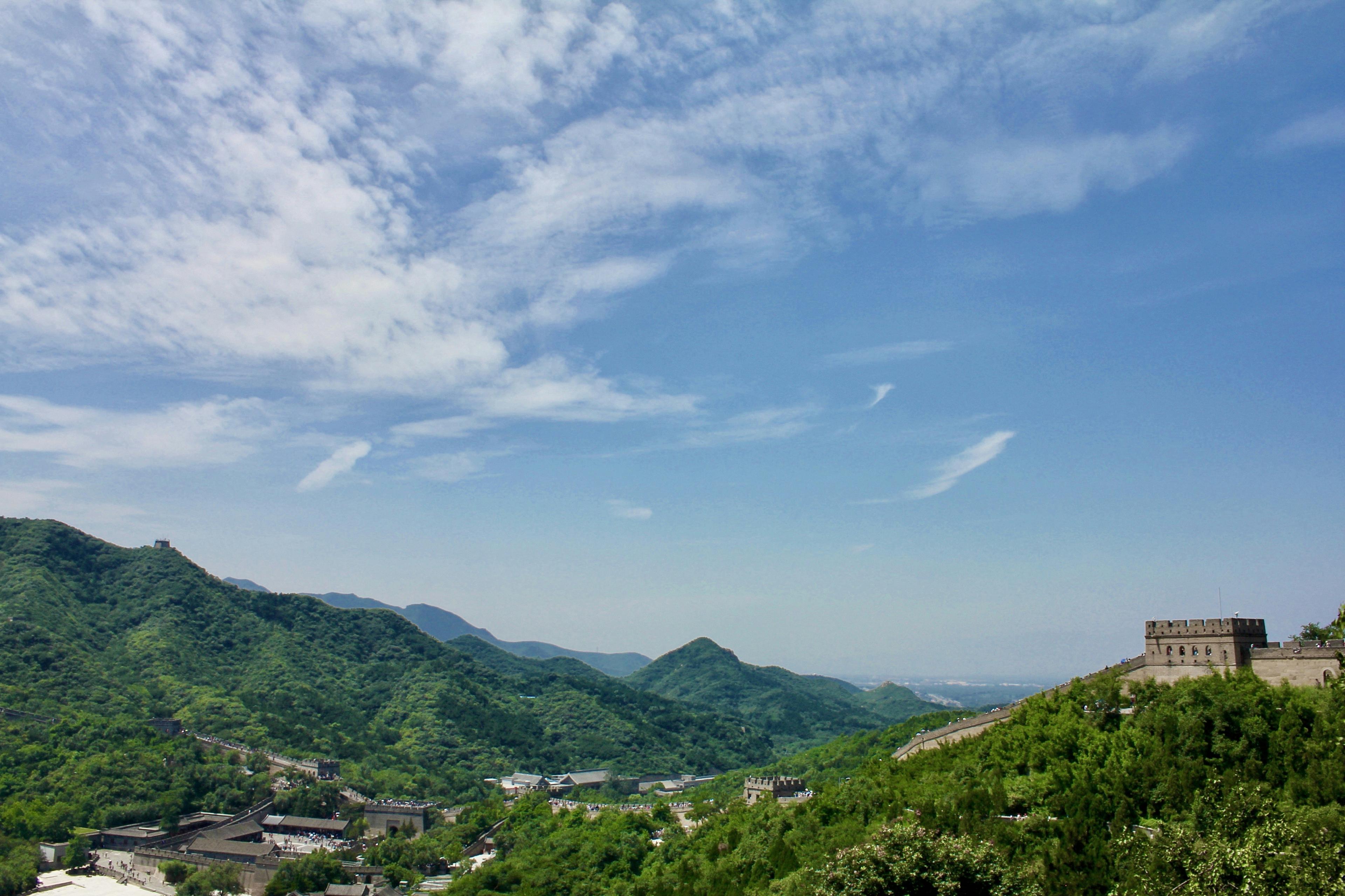 Great Wall of China winding through green mountains under clear blue sky