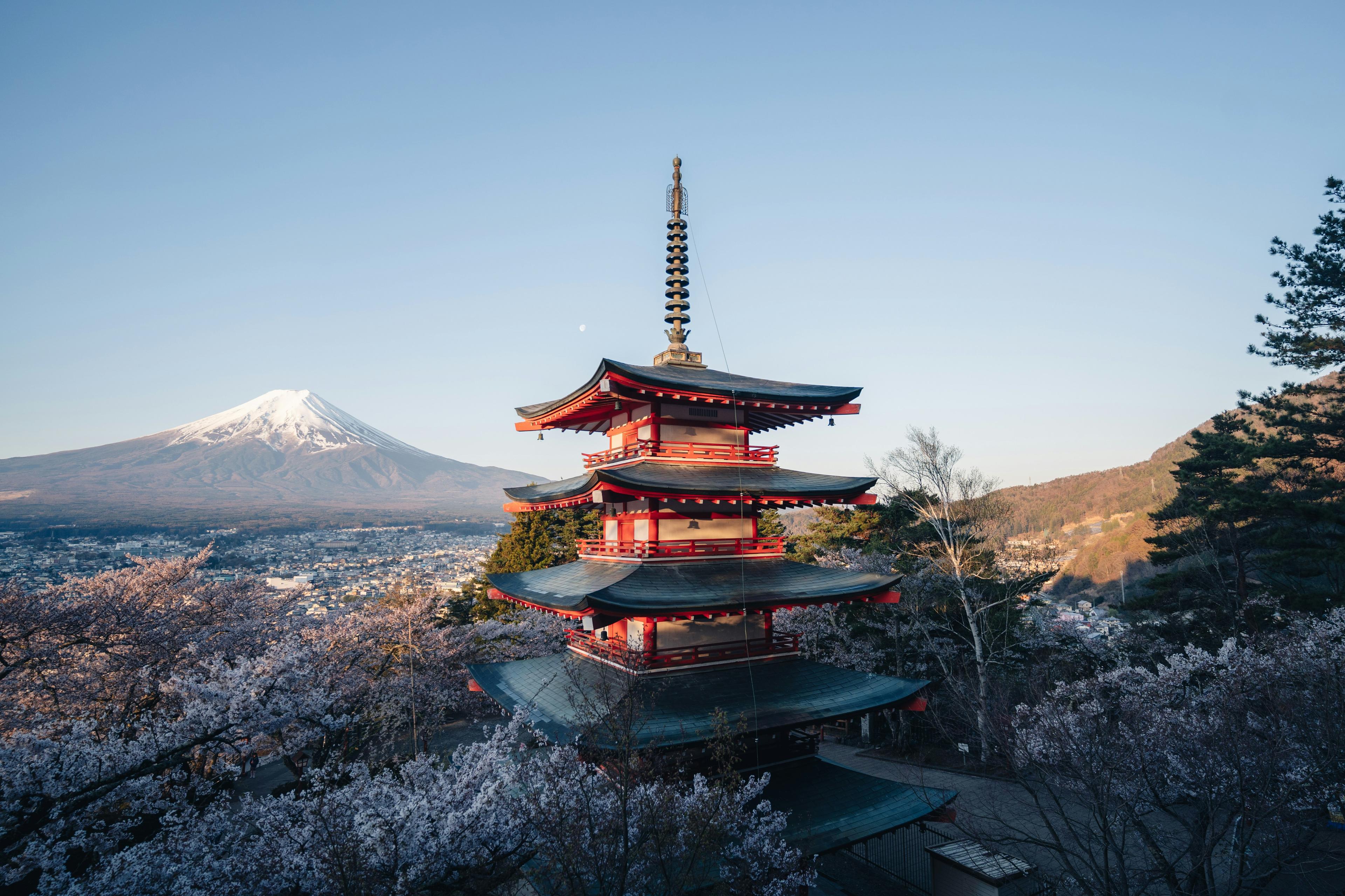 Mount Fuji with cherry blossoms in foreground and traditional Japanese pagoda